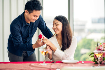 Young handsome romantic asian man giving diamond ring for surprise to girlfriend and talking together in valentine day at the restaurant