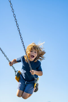 Naklejki Childhood. Funny kid on swing. Little boy swinging on playground. Happy cute excited child on swing. Cute child swinging on a swing. Crazy playful child swinging very high on sky.