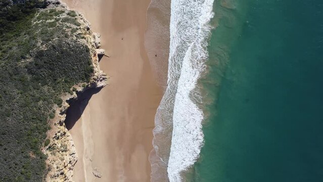 waves rolling at the beach of beliche, beautiful water colors, sunny droneshot from above