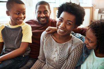 Black family, smile and relax on living room sofa for happy bonding or quality time together at home. African American mother, father and children relaxing and smiling for family holiday on the couch