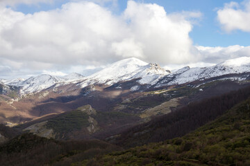 Obraz na płótnie Canvas Cadena de montañas con nieve en las cumbres, en paisaje invernal y cielo con nubes