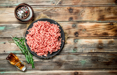 Raw minced meat in a plate with spices and herbs .