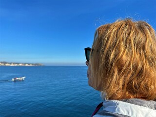 Fototapeta premium Woman looking at the sea and volcano Etna in Sicily, Acitrezza.