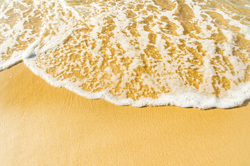 Close-up of a beach with a calm transparent wave. Romantic sea coast with golden sand.