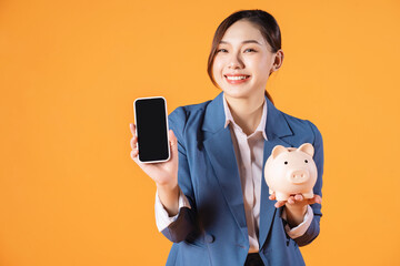 Photo of young Asian businesswoman holding piggy bank on background
