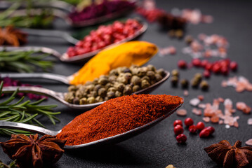Variation of spices in metal spoons paprika, turmeric, cardamom, a mixture of allspice, thyme and rosemary