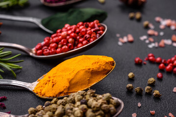 Variation of spices in metal spoons paprika, turmeric, cardamom, a mixture of allspice, thyme and rosemary