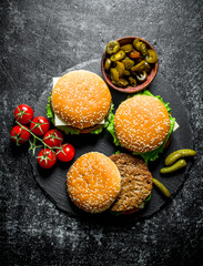 Burgers with tomatoes and gherkins on a stone Board.