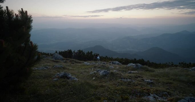 A shot of valley from the mountain Peca, Hiker walkih past in the distance with hiking poles in early morning before sunrise.