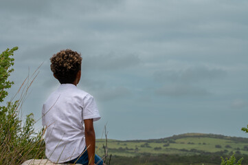 Rear view of young boy sitting on rock