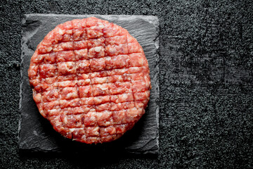 One Raw burger on a stone stand.