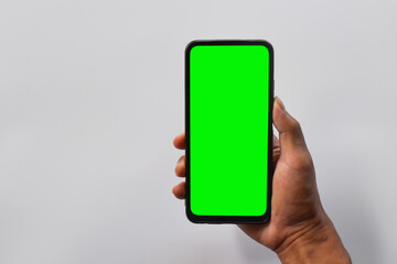 Mock up mobile. Man's hand holding black smartphone with green screen in vertical position isolated on white background.