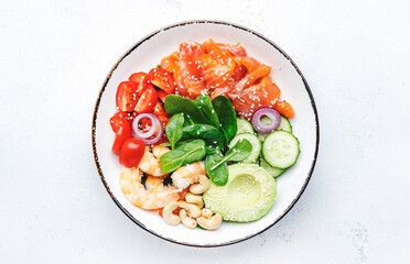 Salmon salad for ketogenic diet with shrimp, avocado, spinach, cucumber, tomato, cashew nuts, sesame. Low-carbohydrate breakfast rich in healthy fats. White table background, top view