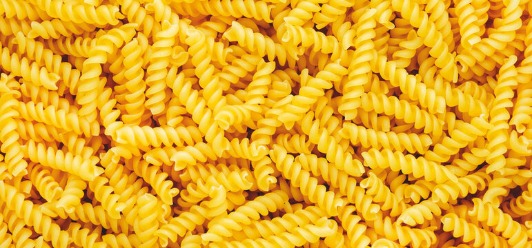 Raw dry fusilli pasta, food background texture, top view horizontal banner