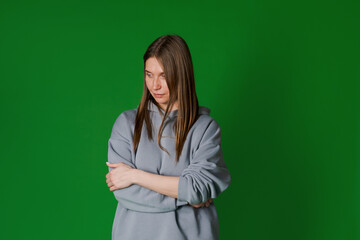 Portrait pretty happy woman, in gray sweatshirt. Charming girl with blond hair, dressed in a stylish sweatshirt. Fashion concept. Isolated on a green background in the studio