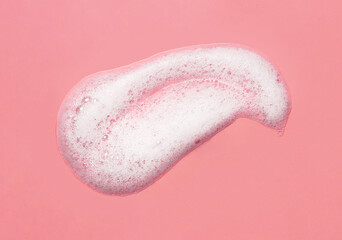 Foam lather texture background. White cleanser gel, shaving foam, shampoo bubbles on pink