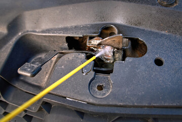 Lubricating car hood lock, spray and cleaning rusty hood lock of car, spraying grease, lubrication...
