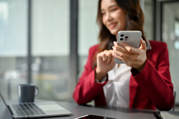 Obraz na płótnie Canvas Attractive Asian businesswoman using her modern smartphone at her desk. selective focus image
