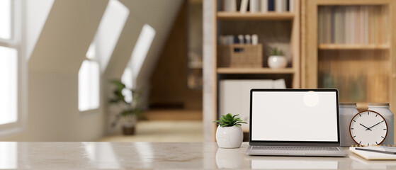 Workspace close-up with laptop mockup, decor and copy space over blurred modern home office