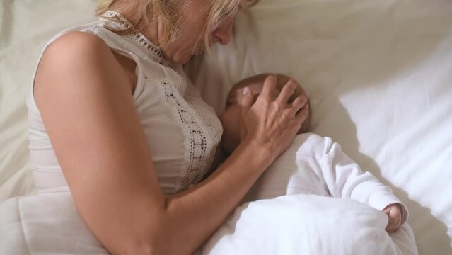 Mom and baby in white clothes. mother breastfeeding newborn baby. woman caressing child. Close-up. care and big love in family. Top view.