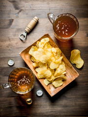Beer in glass mugs and chips on a plate.