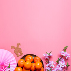 Chinese or lunar new year square flat lay with paper decorations, mandarins and flowers on pink
