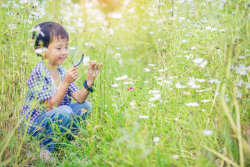 Happiness boy with magnifying glass explorer and learning the nature, flower garden backyard