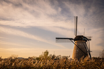 Fototapeta na wymiar sunset silhouette of iconic windmills in Kinderdijk Netherlands. Landmark functional buildings originally made to pump flood water out of low land polder to preserve farm land reclaimed from the sea