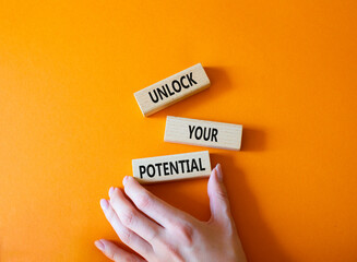 Unlock your Potential symbol. Wooden blocks with words Unlock your Potential. Businessman hand. Beautiful orange background. Business and Unlock your Potential concept. Copy space.