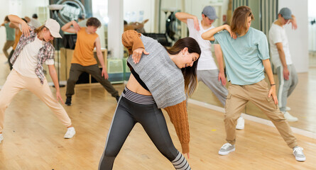 Portrait of expressive teen girl krump dancer in choreographic studio with dancing teenagers in...