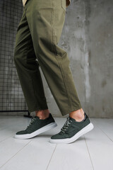 Male legs in pants and green casual sneakers. Men's fashionable shoes