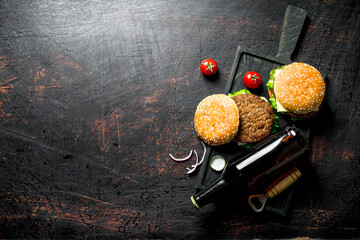 Burgers and beer in a bottle on the cutting Board.