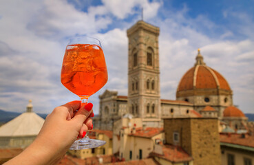 Hand with an Aperol Spritz and a view of the Duomo Cathedral in Florence, Italy