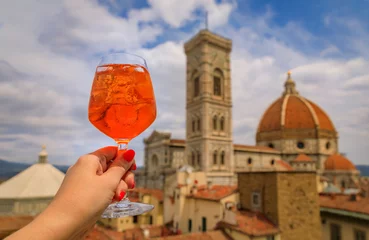 Poster Hand with an Aperol Spritz and a view of the Duomo Cathedral in Florence, Italy © SvetlanaSF