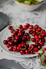 Red ripe cherries on a white plate in kitchen