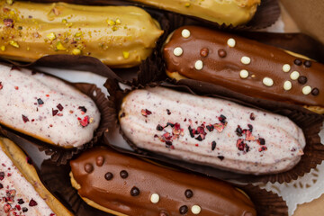 Top view of gourmet eclairs in a box with different colours and tastes