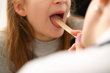 Otorhinolaryngologist examines child girl with sore throat