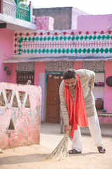 Indian man cleaning house with broom