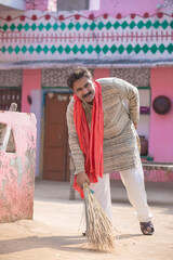 Indian man cleaning house with broom