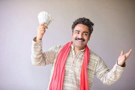 Indian farmer showing money and giving happy expression.