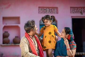 Happy indian farmer couple with little daughter at home.