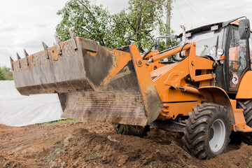 Fototapeta premium Excavator or bulldozer bucket flattens the ground or road in the industrial zone or construction site