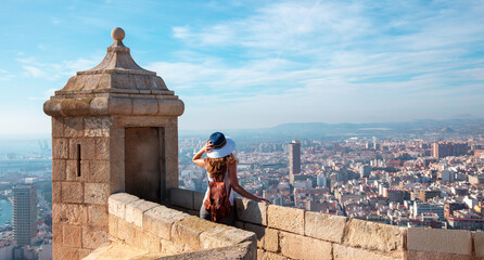 Back view of traveler girl in Alicante, Santa Barbara castle and panoramic city landscape view-...