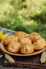 homemade buns or pies in a clay bowl, ears of wheat on a brown wooden background