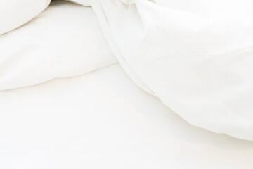 Obraz premium wrinkle messy blanket and white pillow in bedroom after waking up in the morning, from sleeping in a long night, details of duvet and blanket, an unmade bed in hotel bedroom with white blanket