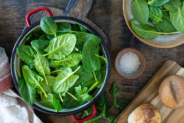 Fresh baby spinach leaves in a bowl and ingredients for making salad.