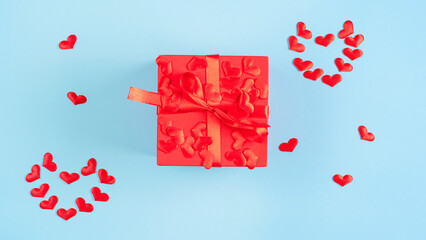 Blurred Blue background decorated with red hearts and red gift box.