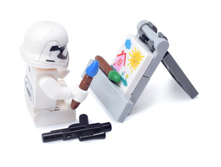 Naklejka premium Lego minifigure of warrior Star Wars as artist is painting a build isolated on white. Editorial illustrative image of popular plastic toy constructor.