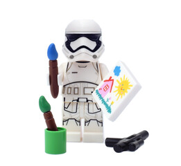 Naklejka premium Lego minifigure of warrior Star Wars as artist is painting a build isolated on white. Editorial illustrative image of popular plastic toy constructor.