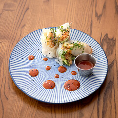Salmon in rice paper with sauce on a plate. Wooden background. High quality photo